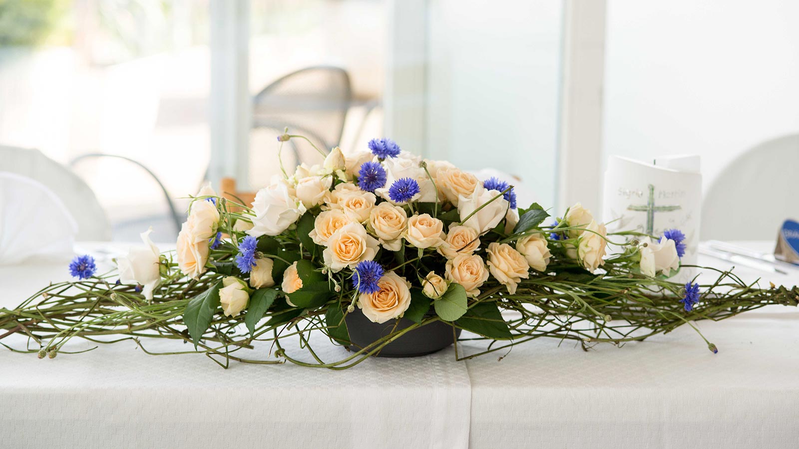 Dekorationselement aus weißen Rosen auf einem Tisch während einer Feier im Restaurant Seilbahn